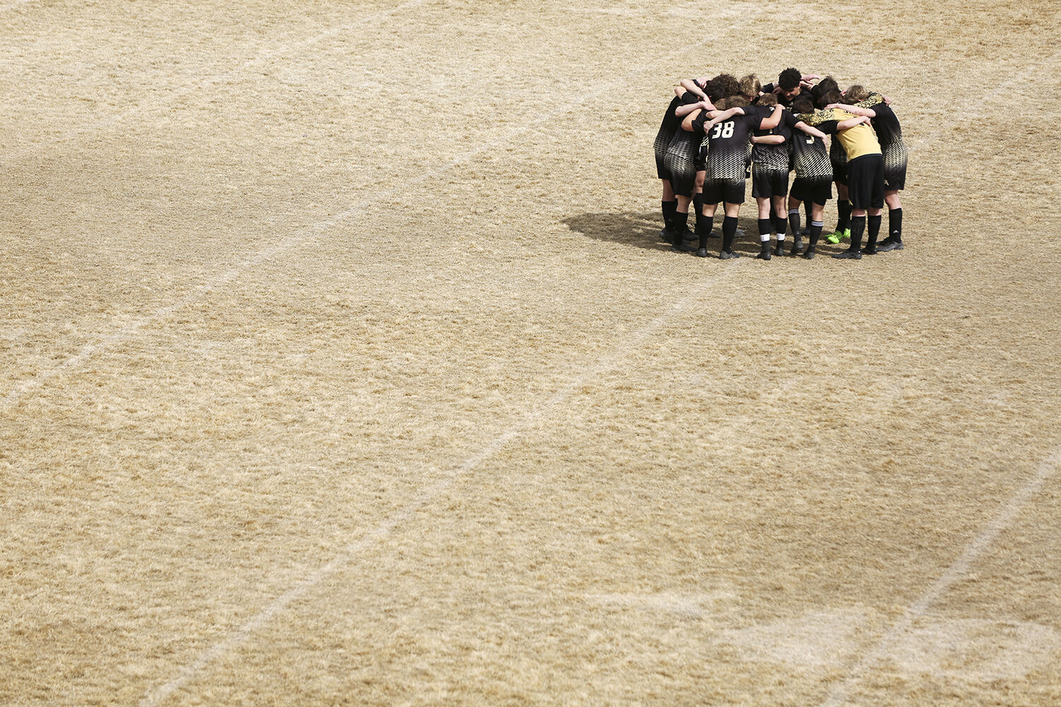 boys soccer huddled together in the center of the field